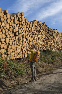 Full length of man standing on log stack against sky