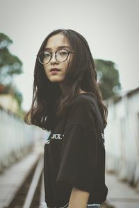 Portrait of young woman wearing eyeglasses standing outdoors