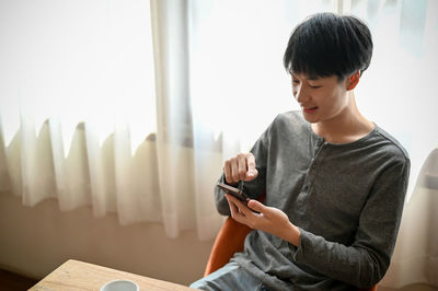 Young woman using mobile phone while sitting at home