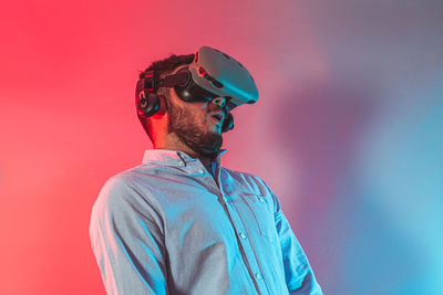 Portrait of man wearing sunglasses standing against red wall