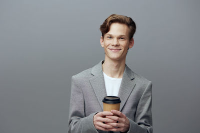 Portrait of young man standing against gray background