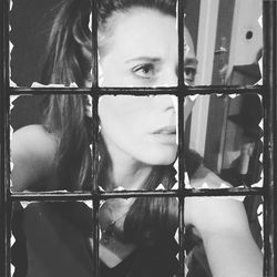 Portrait of young woman standing by metal grate