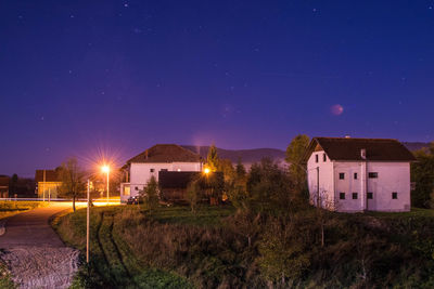 Illuminated buildings against clear sky at night