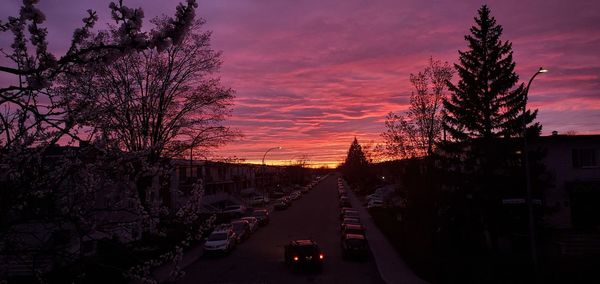 Cars on road against sky at sunset