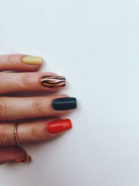 Cropped hand of woman with nail polish over white background