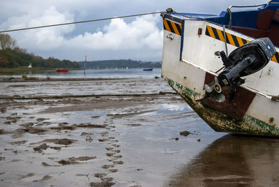 Boat moored on beach against sky