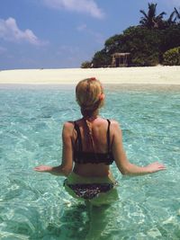 Rear view of young woman in bikini in sea