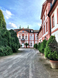 Road amidst trees and buildings against sky