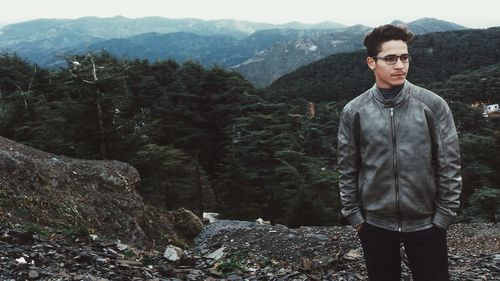 Man looking away while standing against mountains