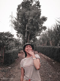 Portrait of girl standing by tree against sky