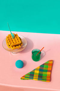 High angle view of waffle, juice, rubber ball and multi colored napkin kept on table