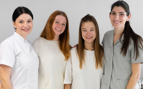 Portrait of smiling friends standing against white background