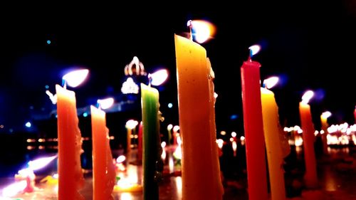 Close-up of candles burning at night