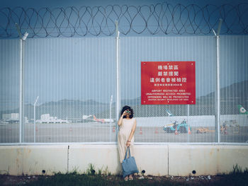 Woman standing by text on wall