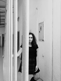 Portrait of woman standing by railing and wall