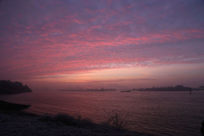 Scenic view of sea against dramatic sky during sunset