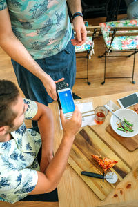 Midsection of man holding mobile phone on table