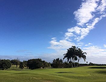 Scenic view of golf course against blue sky