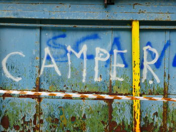 Close-up of rusty sign against blue sky