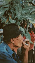 Close-up of man smoking cigarette against plants
