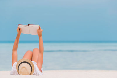 Man relaxing on beach against sky