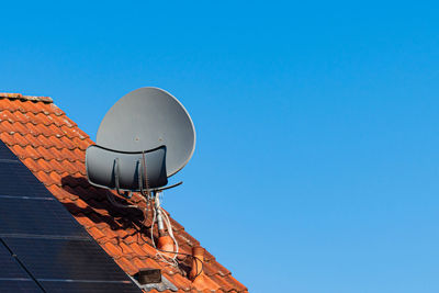 Satellite dish on the roof of a house covered with terracotta tiles. solar panels on the roof. 