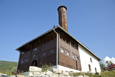 Low angle view of abandoned building against clear blue sky
