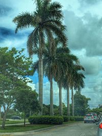 Cars on road against cloudy sky