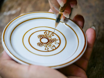 Cropped image of woman making design on saucer