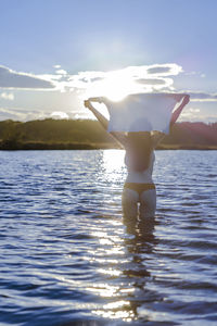 Rear view of man standing in sea against sky