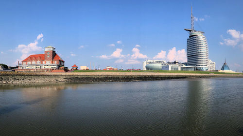 View of buildings by river against cloudy sky