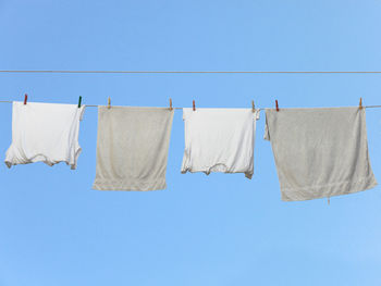 Clothes drying on clothesline against clear blue sky