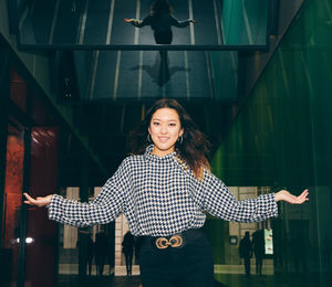 Portrait of smiling young woman standing against wall