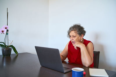 Young woman using mobile phone while sitting on table