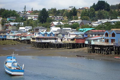 Boats moored in city by buildings against sky