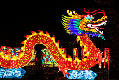 Low angle view of illuminated carousel against sky at night