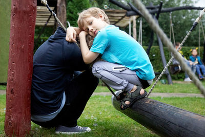 Mature man and grandson crouching in playground