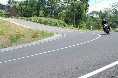 Rear view of man riding motorcycle on road