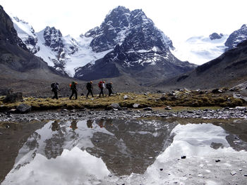 People on snowcapped mountain against sky