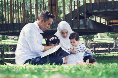 Full length of father with daughter sitting outdoors