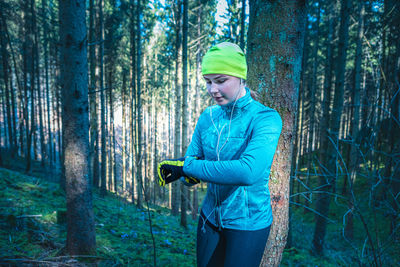 Woman checking time while standing in forest