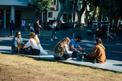 People sitting on sidewalk in city