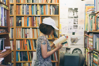 Side view of woman reading book in library