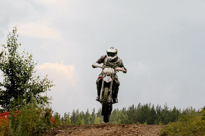 Biker riding motorbike on land against sky