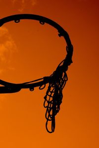 Low angle view of silhouette hanging against orange sky