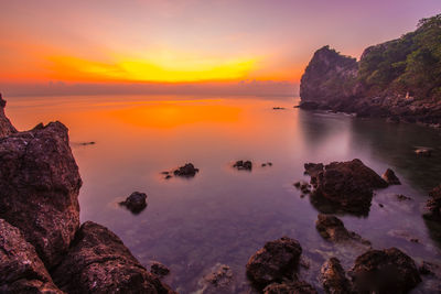 Rocks on sea against sky during sunset