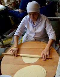 High angle view of senior woman rolling dough on table