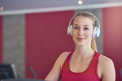 Portrait of smiling young woman listening to music on headphones at gym