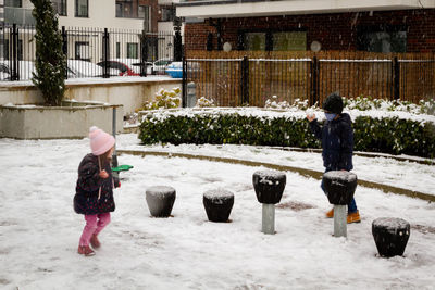 Full length of boy and girl standing in snow