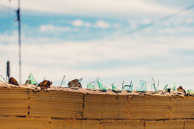 Broken glasses on fence against sky